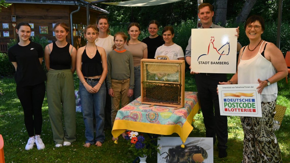 Die neuen Sonnensegel spenden Schatten im Bienengarten: Ilona Munique (rechts) mit Zweitem Bürgermeister Jonas Glüsenkamp und der Umweltgruppe des Eichendorff Gymnasiums an der Bienen-InfoWabe. Quelle: Stadt Bamberg Pressestelle, Sebastian Martin