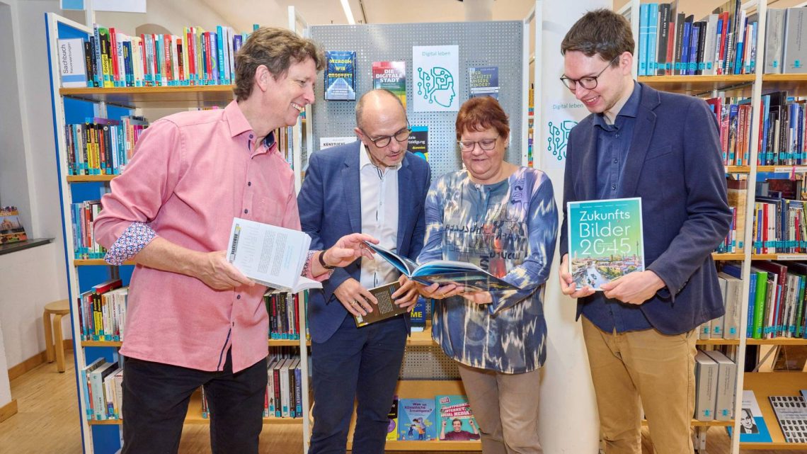 Stolz auf das neue Bücherregal (v.l.n.r.): Sascha Götz (Programmleiter Smart City Bamberg), Dr. Stefan Goller (Referent für Wirtschaft und Digitalisierung), Christiane Weiß (Leiterin Stadtbücherei Bamberg) und Franz Schäfer (lesebegeisterter Datenarchitekt bei Smart City Bamberg), Quelle: Stadtarchiv Bamberg, Nadine Gumpert