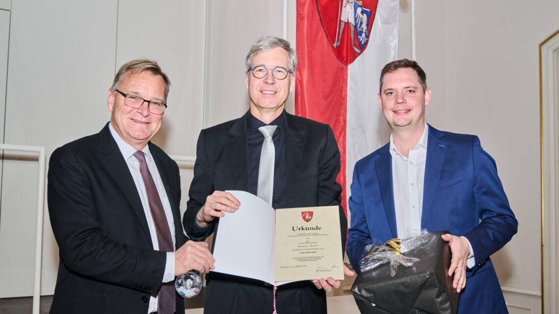 Oberbürgermeister Andreas Starke (l.) sowie Bürgermeister und
Personalreferent Jonas Glüsenkamp (r.) übergeben die RuhestandsUrkunde an Thomas Beese. Quelle: Stadtarchiv Bamberg, Jürgen Schraudner