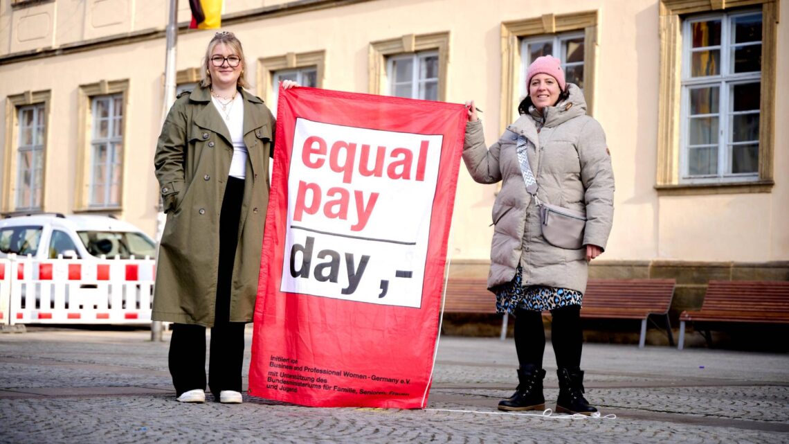 Elena Hümmer und Nina Köhler von der
Gleichstellungsstelle hissen die Fahne zum Equal Pay Day vor dem
Rathaus Maxplatz. Quelle: Stadt Bamberg, Sonja Seufferth