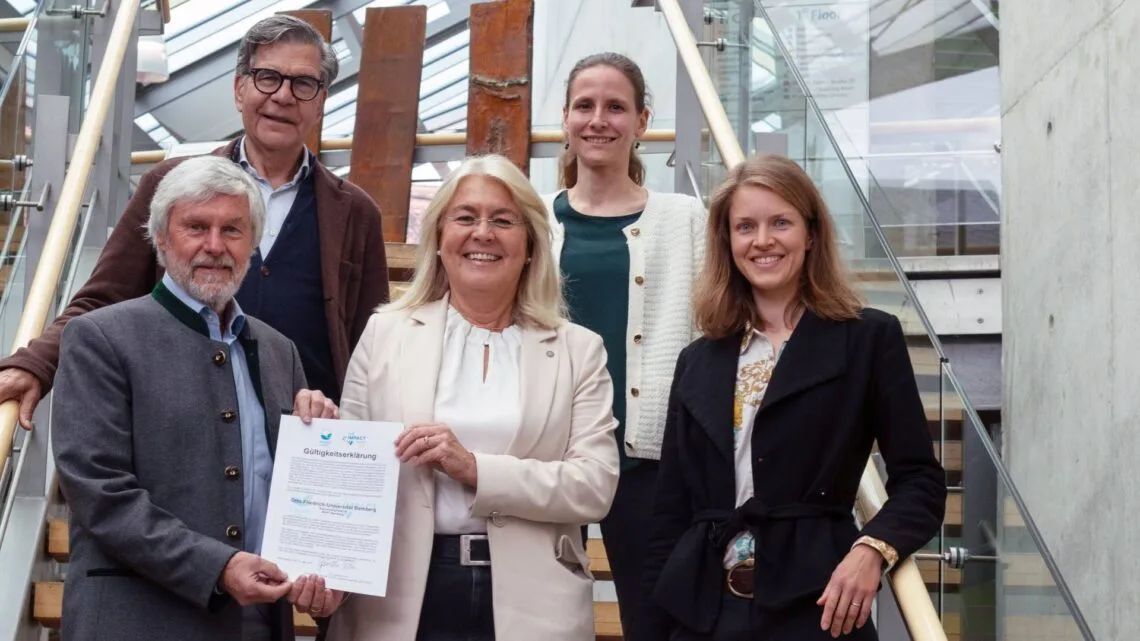 Die Gutachter Günther Rau (vorne l.) und Burkhard Kühnemann (hinten l.) übergeben die Gültigkeitserklärung an Kanzlerin Dagmar Steuer-Flieser (Mitte) und Antonia Schott-Bartning (vorne r.) und Theresa Riedl (hinten r.). Quelle: Emma Seeger/Universität Bamberg