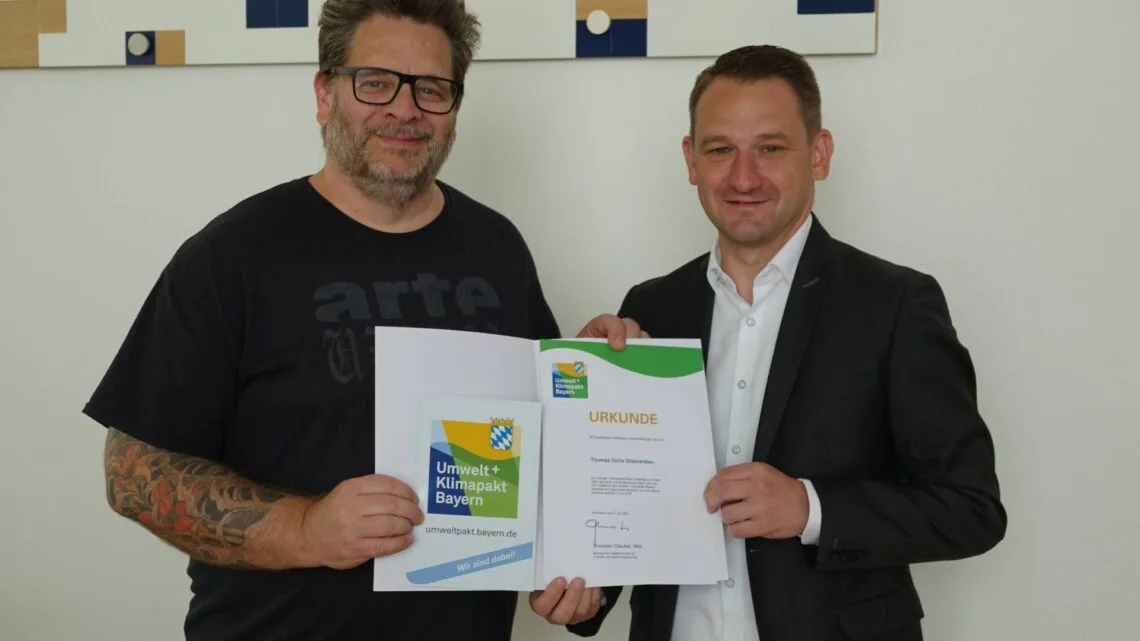 Landrat Johannes Maciejonczyk überreicht die Urkunde zum „Umweltpakt Bayern“ an Gitarrenbaumeister Thomas Ochs. (Quelle: Landratsamt Bamberg)