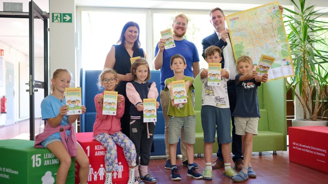 Schulleiterin Jasmin Kremer, Maxi Manlig vom Stadtjugendring
und Bürgermeister Jonas Glüsenkamp (v.l.) zeigen gemeinsamen mit
Kindern der Hainschule den überarbeiteten Kinderstadtplan. Quelle:  Stadt Bamberg, Sonja Seufferth